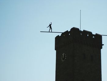 Low angle view of silhouette bird on roof against clear sky