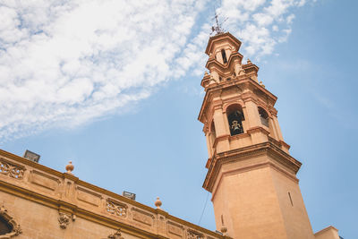 Low angle view of clock tower amidst buildings against sky