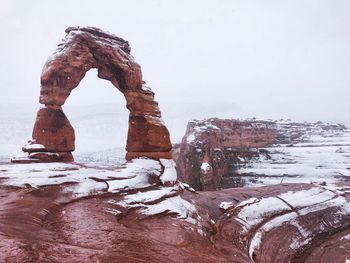 Frozen rock formation against sky during winter