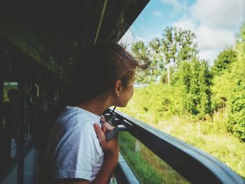 Side view of girl looking through train window