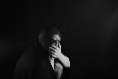 Portrait of woman looking away against black background