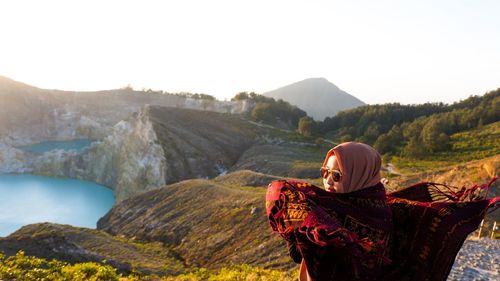 Rear view of woman wearing scarf standing against mountain