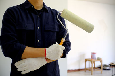 Midsection of man holding paint roller
