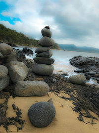 Stack of stones on beach against sky