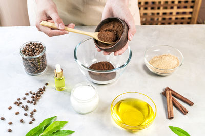 Woman mixing ingredients preparing coffee scrub for skin treatment