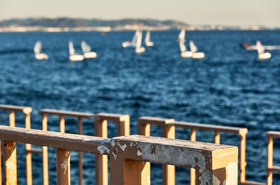 Railing by sea against sky and yacht
