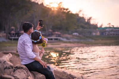 Man taking selfie with girlfriend while sitting at beach