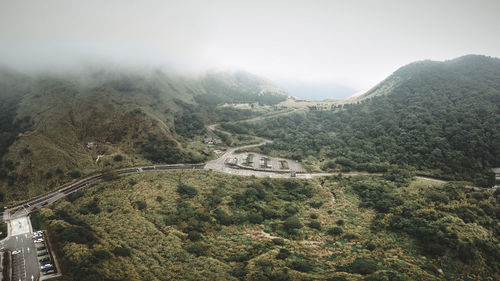 Aerial view of road and parking lot amidst trees against sky