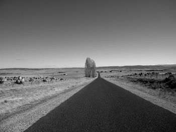 Road amidst field against clear sky