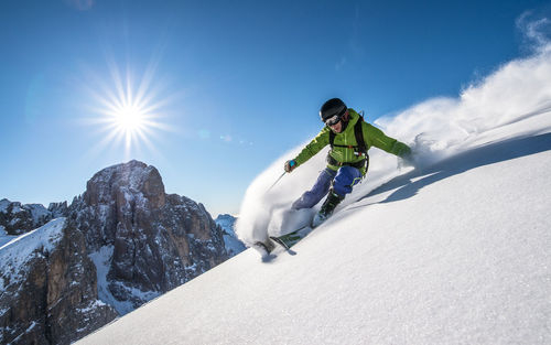 Man skiing on snowcapped mountain against sky