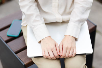 Close-up of woman using cell phone and laptop