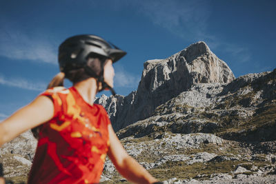 Female cyclist looking at rock mountain on sunny day, picos de europa national park, cantabria, spain