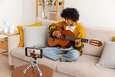 Young woman using laptop while sitting on sofa at home