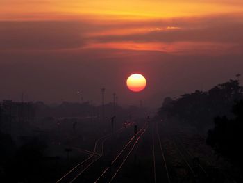 Railroad tracks against sky during sunset