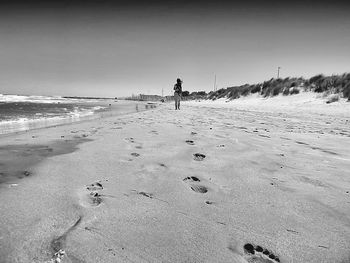 Man walking on beach against clear sky