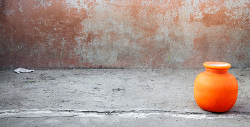 Close-up of orange bottle against wall