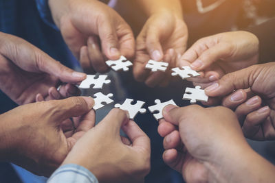 Cropped hands of people holding jigsaw pieces