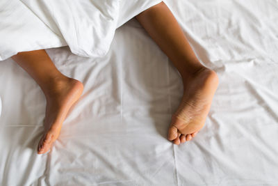 Low section of baby lying on bed