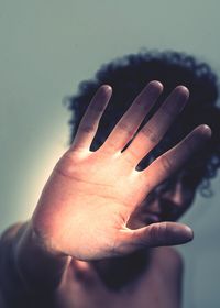 Close-up of woman showing stop gesture against wall