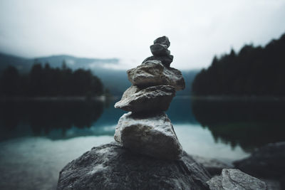Stack of rocks by lake against sky