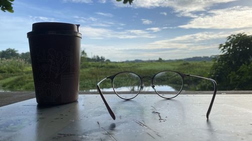 Close-up of eyeglasses on table against sky