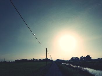 Road amidst field against sky during sunset