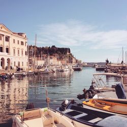 Sailboats moored in sea against buildings in city