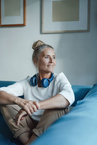 Woman with wireless headphones sitting on sofa