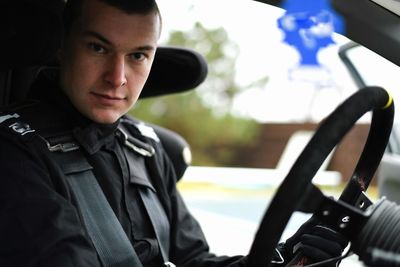 Portrait of young man wearing uniform sitting in car