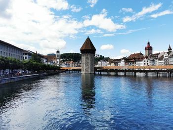 Bridge over river by buildings against sky in city