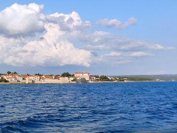 Scenic view of sea by buildings against sky