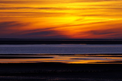 Scenic view of sea against dramatic sky during sunset