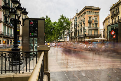 Blurred motion of people walking on footpath in city