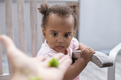 A female toddler staring at a piece of broccoli