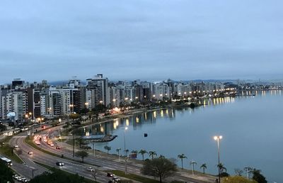 High angle view of illuminated city by buildings against sky