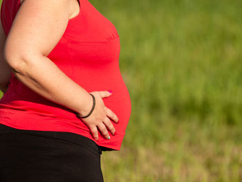 Midsection of pregnant woman standing outdoors