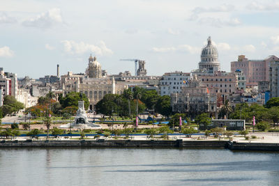 City at waterfront against cloudy sky