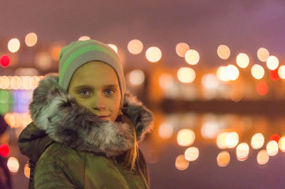 Side view portrait of girl standing in illuminated city at night