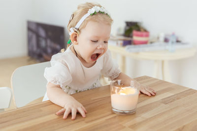 Cute deaf girl looking at candle on table