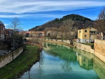 River amidst houses and buildings against sky