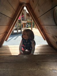 Cute baby girl kneeling on wood