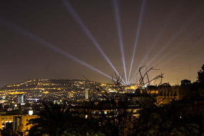 Illuminated cityscape against sky at night