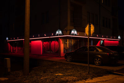 Cars on street against illuminated buildings in city at night