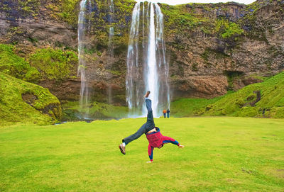 
jumping man in front of a waterfall in iceland 