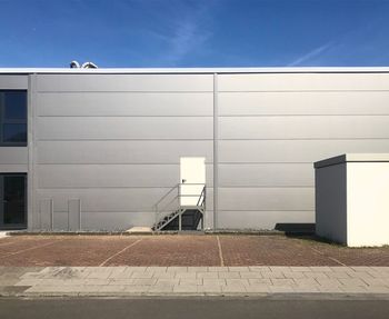 White wall by building against sky