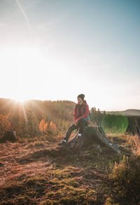 Active hiker sitting on a stump enjoys the feeling of reaching the top of the mountain at sunrise
