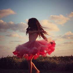 Woman with red umbrella against sunset sky