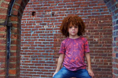 Portrait of a girl standing against brick wall