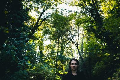 Portrait of woman standing against trees in forest