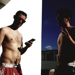 Full length of shirtless man using mobile phone